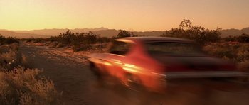Movie still from “The Fast and the Furious” (2001), directed by Rob Cohen – A car is driving down a dirt road at sunset; Wide shot, Low angle