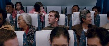 Movie still from “The Fast and the Furious: Tokyo Drift” (2006), directed by Justin Lin – A group of people sitting in a row of seats on an airplane; Medium shot, Over the shoulder angle