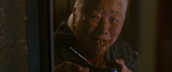 Movie still from “The Fast and the Furious: Tokyo Drift” (2006), directed by Justin Lin – An older woman eating a bowl of noodles with chopsticks; Close Up shot, High angle