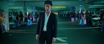 Movie still from “The Fast and the Furious: Tokyo Drift” (2006), directed by Justin Lin – A man in a suit standing in a parking lot; Medium shot, Low angle