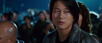 Movie still from “The Fast and the Furious: Tokyo Drift” (2006), directed by Justin Lin – A man with long black hair is looking at the camera; Close Up shot, Over the shoulder angle