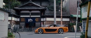 Movie still from “The Fast and the Furious: Tokyo Drift” (2006), directed by Justin Lin – An orange sports car parked on the side of the road; Wide shot, Low angle