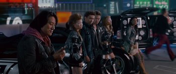 Movie still from “The Fast and the Furious: Tokyo Drift” (2006), directed by Justin Lin – A group of people standing next to each other in front of a car; Medium shot, Over the shoulder angle
