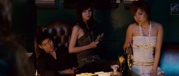 Movie still from “The Fast and the Furious: Tokyo Drift” (2006), directed by Justin Lin – A woman sitting at a table with two other people; Medium shot, Low angle