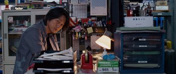 Movie still from “The Fast and the Furious: Tokyo Drift” (2006), directed by Justin Lin – A man sitting in front of a desk in a store; Medium shot, Over the shoulder angle