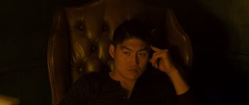 Movie still from “The Fast and the Furious: Tokyo Drift” (2006), directed by Justin Lin – A man sitting on a leather chair in a dark room; Close Up shot, High angle