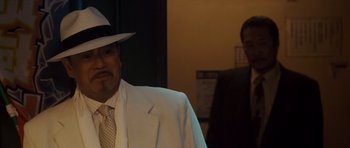 Movie still from “The Fast and the Furious: Tokyo Drift” (2006), directed by Justin Lin – A man wearing a white suit and a white hat; Close Up shot, Over the shoulder angle