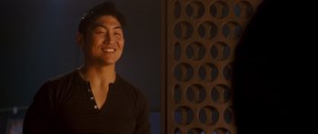 Movie still from “The Fast and the Furious: Tokyo Drift” (2006), directed by Justin Lin – A young man smiling for the camera in front of a wooden screen; Close Up shot, Over the shoulder angle