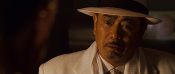 Movie still from “The Fast and the Furious: Tokyo Drift” (2006), directed by Justin Lin – A person wearing a suit and a hat; Close Up shot, Over the shoulder angle