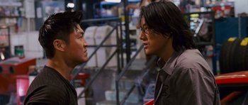 Movie still from “The Fast and the Furious: Tokyo Drift” (2006), directed by Justin Lin – Two asian men talking to each other in a warehouse; Close Up shot, Over the shoulder angle