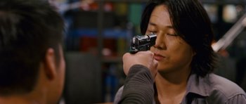 Movie still from “The Fast and the Furious: Tokyo Drift” (2006), directed by Justin Lin – A man holding a camera up to his face; Close Up shot, Over the shoulder angle