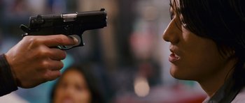 Movie still from “The Fast and the Furious: Tokyo Drift” (2006), directed by Justin Lin – A woman holding a gun up to her face; Close Up shot, Over the shoulder angle