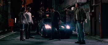 Movie still from “The Fast and the Furious: Tokyo Drift” (2006), directed by Justin Lin – A group of men standing next to each other on a street; Wide shot, Over the shoulder angle