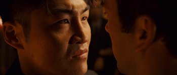 Movie still from “The Fast and the Furious: Tokyo Drift” (2006), directed by Justin Lin – A man's face with another man's face in front of him; Close Up shot, Over the shoulder angle