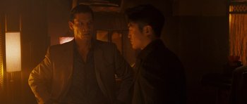 Movie still from “The Fast and the Furious: Tokyo Drift” (2006), directed by Justin Lin – Two men are talking in a dimly - lit room; Medium shot, Over the shoulder angle