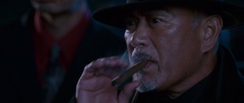 Movie still from “The Fast and the Furious: Tokyo Drift” (2006), directed by Justin Lin – An older man is smoking a cigar in a dark room; Close Up shot, Low angle