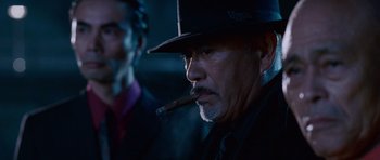 Movie still from “The Fast and the Furious: Tokyo Drift” (2006), directed by Justin Lin – A person wearing a hat and smoking a cigar; Close Up shot, Low angle