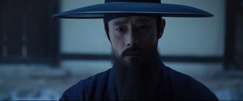 Movie still from “The Fortress” (2017), directed by Hwang Dong-hyuk – A man with a long beard wearing a hat; Close Up shot, Low angle