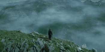 Movie still from “The Girl in the Mirror” (2022), created by Sergio G. Sánchez – A man standing on top of a mountain looking at the sky; Extreme Wide shot, High angle