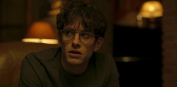 Movie still from “The Girl in the Mirror” (2022), created by Sergio G. Sánchez – A young man with glasses is looking at the camera; Close Up shot, Over the shoulder angle