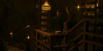 Movie still from “The Girl in the Mirror” (2022), created by Sergio G. Sánchez – Two people standing in a dark room next to a wooden railing; Wide shot, Low angle