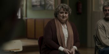 Movie still from “The Girl in the Mirror” (2022), created by Sergio G. Sánchez – An older woman sitting on a chair in a room; Close Up shot, Over the shoulder angle