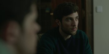 Movie still from “The Girl in the Mirror” (2022), created by Sergio G. Sánchez – A person sitting on a couch; Close Up shot, Over the shoulder angle