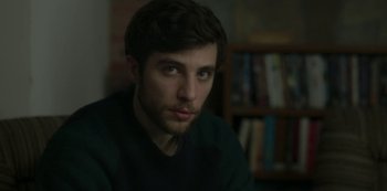 Movie still from “The Girl in the Mirror” (2022), created by Sergio G. Sánchez – A person sitting in front of a bookshelf; Close Up shot, Over the shoulder angle