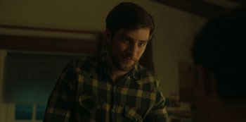 Movie still from “The Girl in the Mirror” (2022), created by Sergio G. Sánchez – A man in a plaid shirt is looking at the camera; Close Up shot, Over the shoulder angle