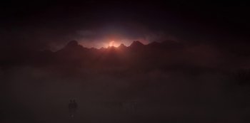 Movie still from “The Girl in the Mirror” (2022), created by Sergio G. Sánchez – Two people are standing in the distance in front of a mountain range; Extreme Wide shot, Low angle