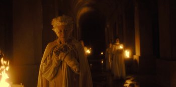 Movie still from “The Girl in the Mirror” (2022), created by Sergio G. Sánchez – A woman in a white dress holding a candle in a dark room; Medium shot, Over the shoulder angle