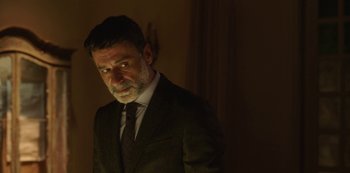 Movie still from “The Girl in the Mirror” (2022), created by Sergio G. Sánchez – A man wearing a suit and tie standing in a room; Close Up shot, Over the shoulder angle