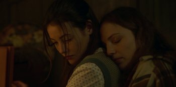 Movie still from “The Girl in the Mirror” (2022), created by Sergio G. Sánchez – Two young women sleeping next to each other on a bed; Close Up shot, Low angle