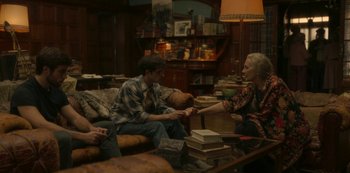 Movie still from “The Girl in the Mirror” (2022), created by Sergio G. Sánchez – A group of people sitting on a couch in a living room; Medium shot, High angle