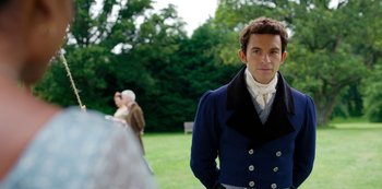 Movie still from “Bridgerton” (2020), created by Chris Van Dusen – A man standing in front of a bench in a park; Medium shot, Over the shoulder angle