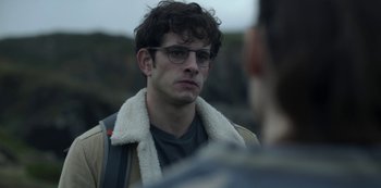 Movie still from “The Girl in the Mirror” (2022), created by Sergio G. Sánchez – A young man wearing glasses and a jacket; Close Up shot, Over the shoulder angle