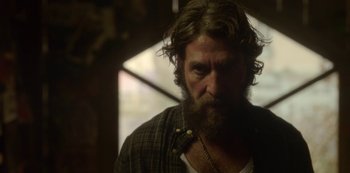 Movie still from “The Girl in the Mirror” (2022), created by Sergio G. Sánchez – A man with a long beard and a necklace; Close Up shot, Over the shoulder angle