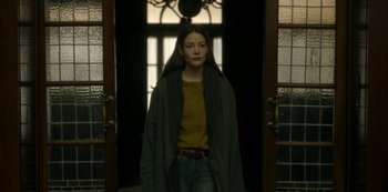 Movie still from “The Girl in the Mirror” (2022), created by Sergio G. Sánchez – A woman standing in front of an open door; Medium shot, Low angle