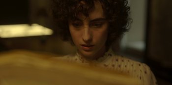 Movie still from “The Girl in the Mirror” (2022), created by Sergio G. Sánchez – A woman with curly brown hair looking at a mirror; Close Up shot, High angle