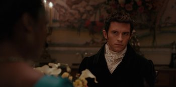 Movie still from “Bridgerton” (2020), created by Chris Van Dusen – A man in a black jacket and a white shirt is in front of flowers; Close Up shot, Over the shoulder angle