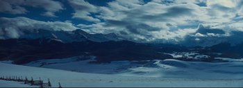 Movie still from “The Hateful Eight” (2015), directed by Quentin Tarantino – A view of a snowy mountain range with a cloudy sky above it; Extreme Wide shot, High angle