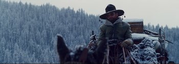 Movie still from “The Hateful Eight” (2015), directed by Quentin Tarantino – A man riding a horse drawn carriage in the snow; Medium shot, Low angle
