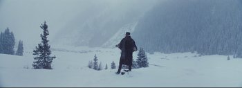 Movie still from “The Hateful Eight” (2015), directed by Quentin Tarantino – A man standing in the snow holding a snowboard; Wide shot, Low angle