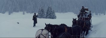 Movie still from “The Hateful Eight” (2015), directed by Quentin Tarantino – A group of horses being pulled in the snow by a man; Wide shot, Low angle