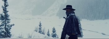 Movie still from “The Hateful Eight” (2015), directed by Quentin Tarantino – A man with a beard and a hat walking in the snow; Medium shot, Low angle
