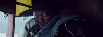 Movie still from “The Hateful Eight” (2015), directed by Quentin Tarantino – A person wearing a hat and holding a cell phone; Close Up shot, Low angle