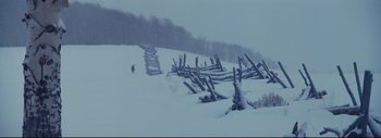 Movie still from “The Hateful Eight” (2015), directed by Quentin Tarantino – A person walking in the snow near a wooden fence; Extreme Wide shot, Low angle