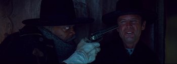 Movie still from “The Hateful Eight” (2015), directed by Quentin Tarantino – A man holding a gun pointed at another man's face; Close Up shot, Over the shoulder angle