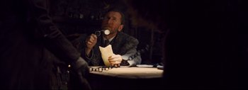 Movie still from “The Hateful Eight” (2015), directed by Quentin Tarantino – A man sitting at a dinner table holding a spoon in front of his mouth; Medium shot, Low angle