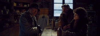 Movie still from “The Hateful Eight” (2015), directed by Quentin Tarantino – Two men sitting at a wooden table in front of a window; Medium shot, Over the shoulder angle